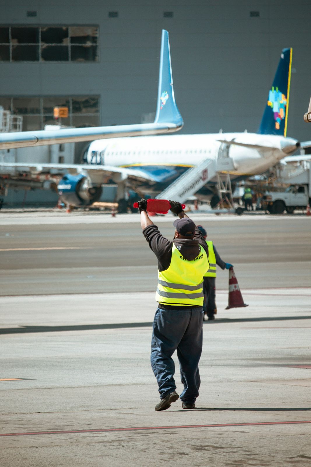 Agent de piste en gilet jaune guidant un avion